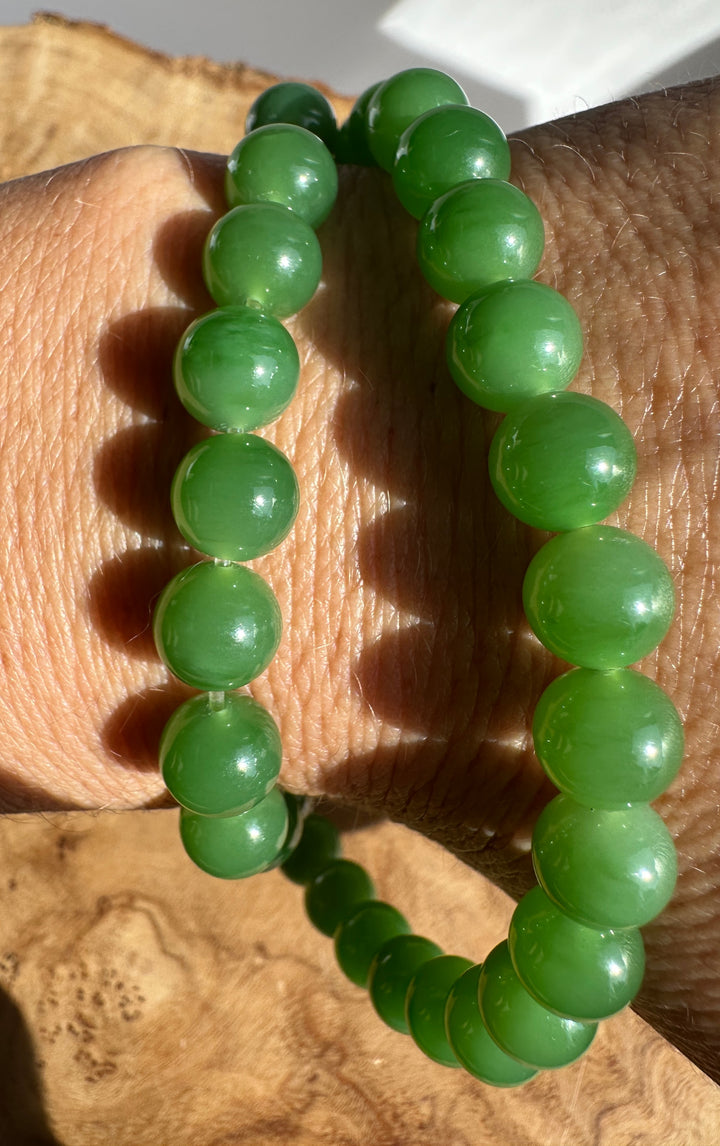 Beaded bracelet of 8mm green spheres worn on the wrist in daylight