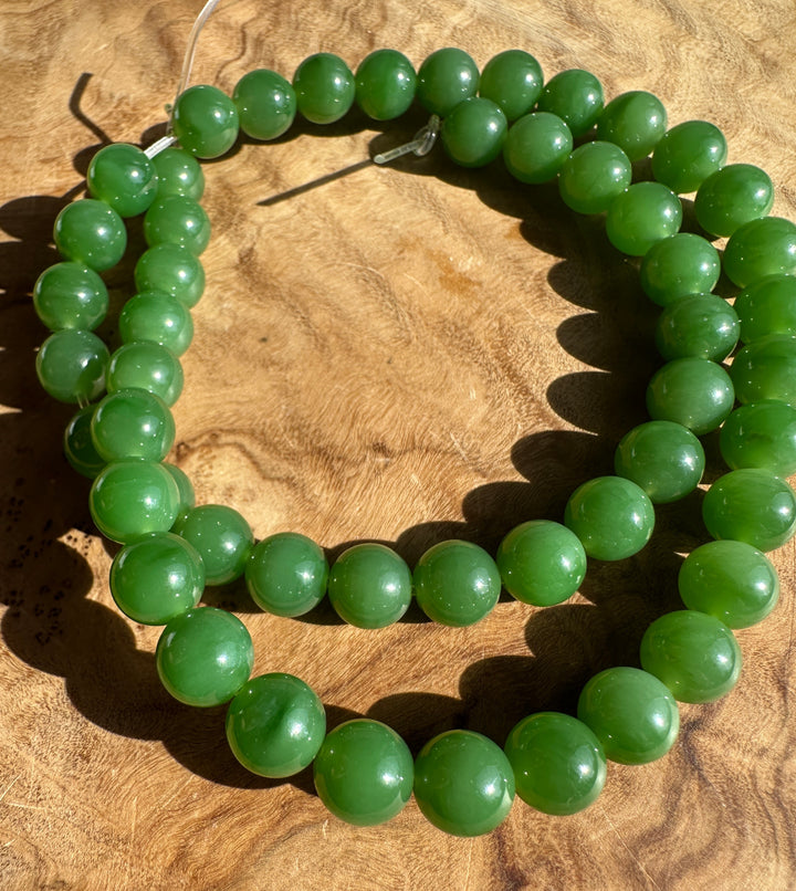 8mm green Siberian jade beads on a clear thread with exposed ends on a tan surface