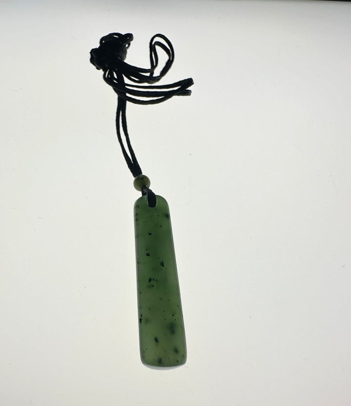 Green jade pendant on a white lite background, black cord
