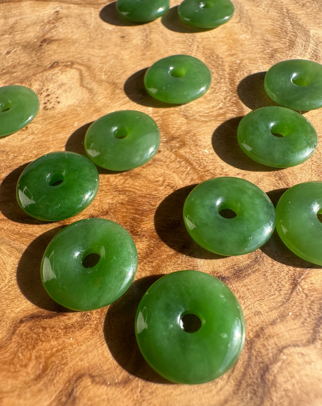 AA Siberian Jade PI 13mm donut beads scattered on a wooden surface