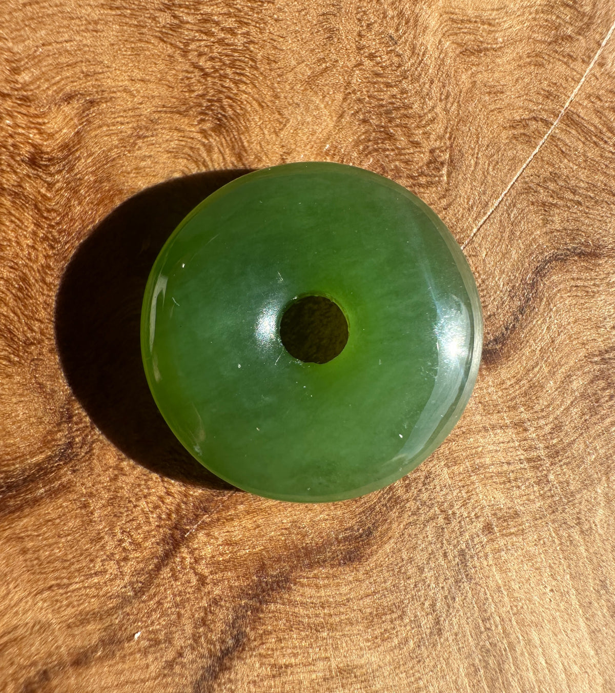 AA Siberian Jade PI 13mm donut bead with a US quarter for scale on wood