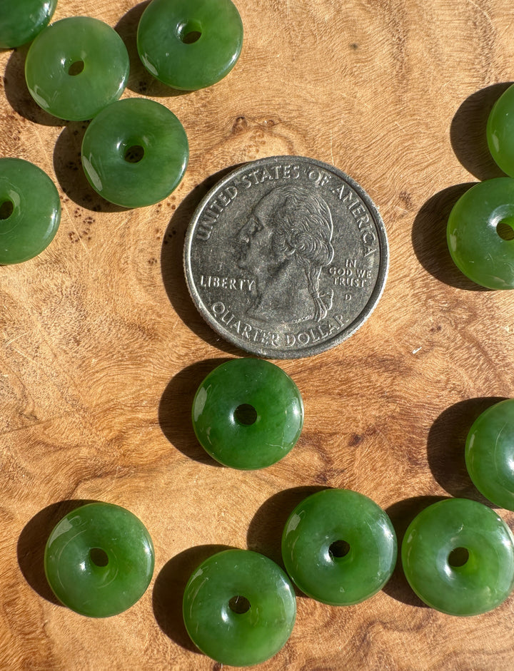 AA Siberian Jade PI 13mm donut beads arranged around a US quarter on a wooden surface