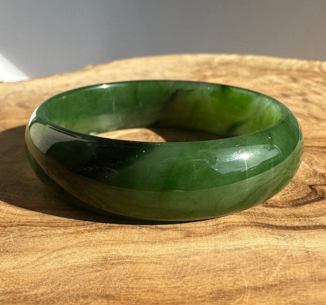 Canadian Jade Bangle 55.5 x 16mm partially visible against a gray backdrop