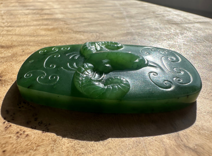 Side view of green jade Ram Pendant highlighting the ram head and intricate scrollwork.