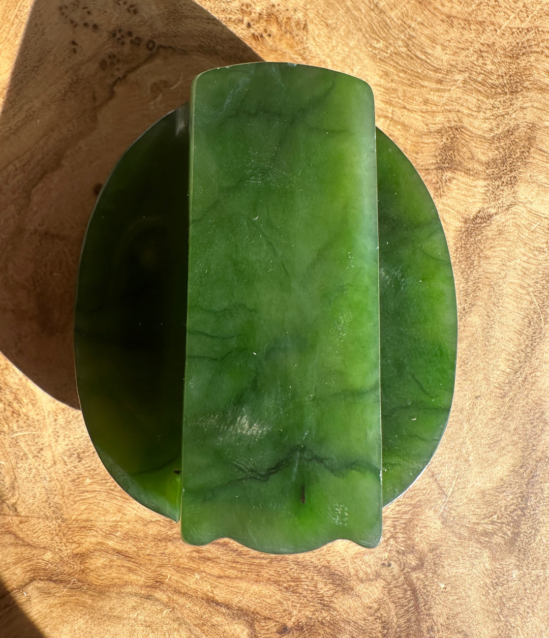 Top view of a green jade belt buckle showing a smooth surface and an oval inner recess.