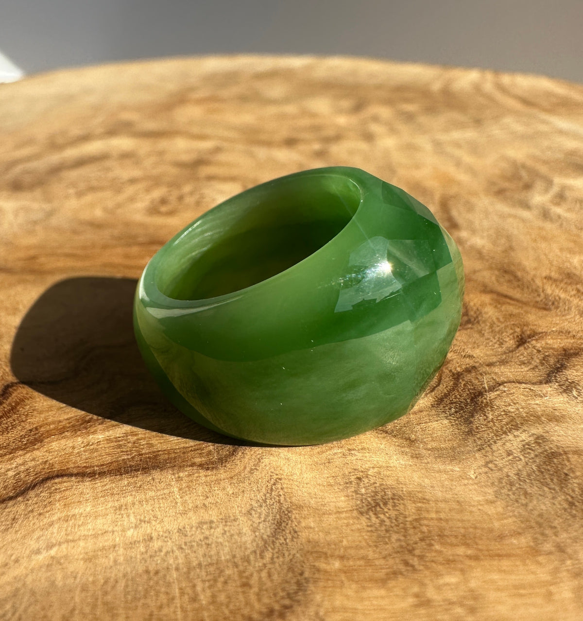 Close up of a vibrant green jade gemstone with facets on a brown textured background