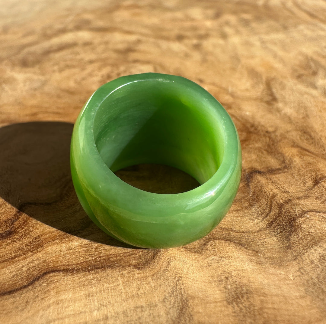Bright green jade ring resting on a wooden surface with the circular opening visible
