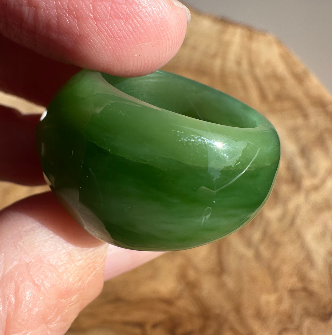 Thumb and forefinger grip a green jade ring from the side