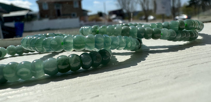 Guatemalan jadeite rondelle bracelet coiled on a sunlit outdoor surface