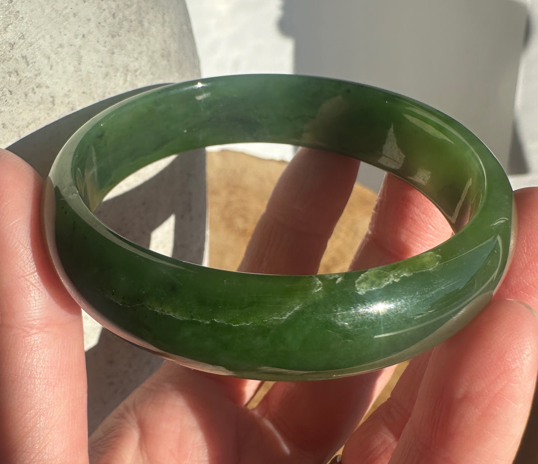 A green jadeite bangle bracelet held in a person&