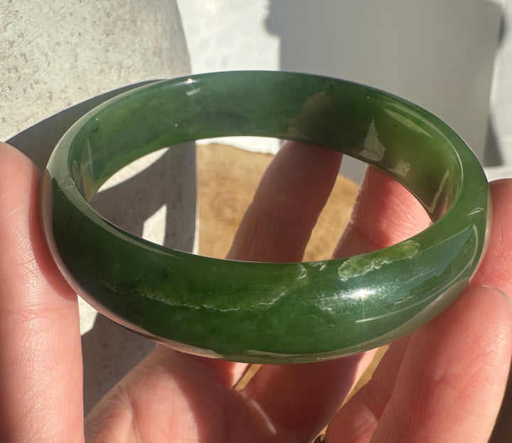 A green jadeite bangle bracelet held in a person&