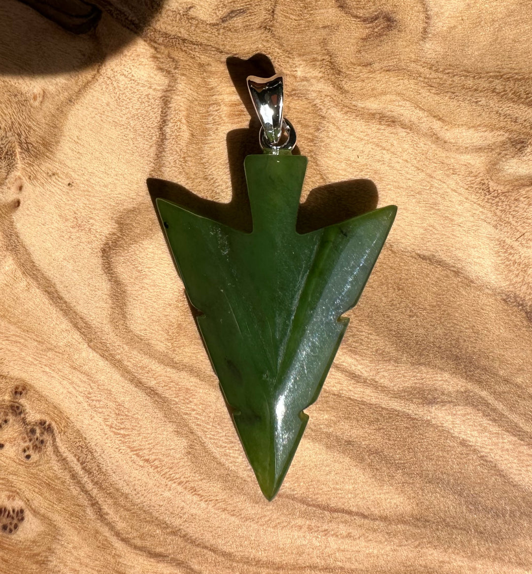 Close up of Canadian Jade Arrow Pendant 31mm on wood