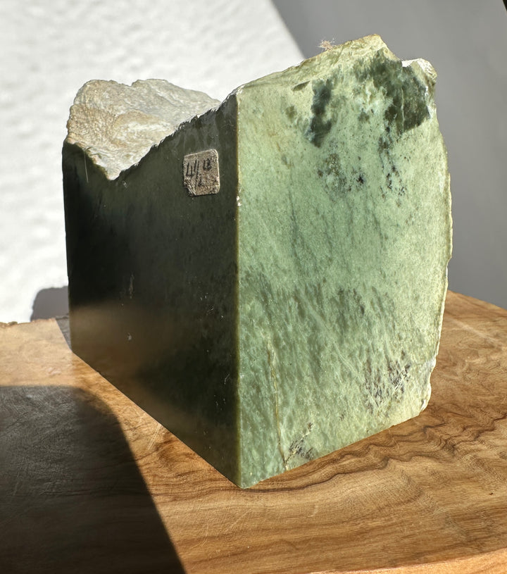 Wyoming Rough Jade block with a green mottled surface and jagged top resting on a wooden table