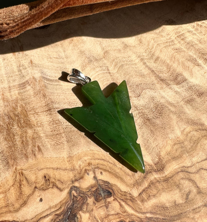 Canadian Jade Arrow Pendant 31mm resting on a wooden surface