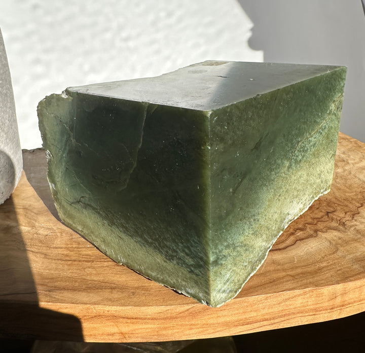 Wyoming Rough Jade chunk showing a flat top and dark green base on a wooden surface