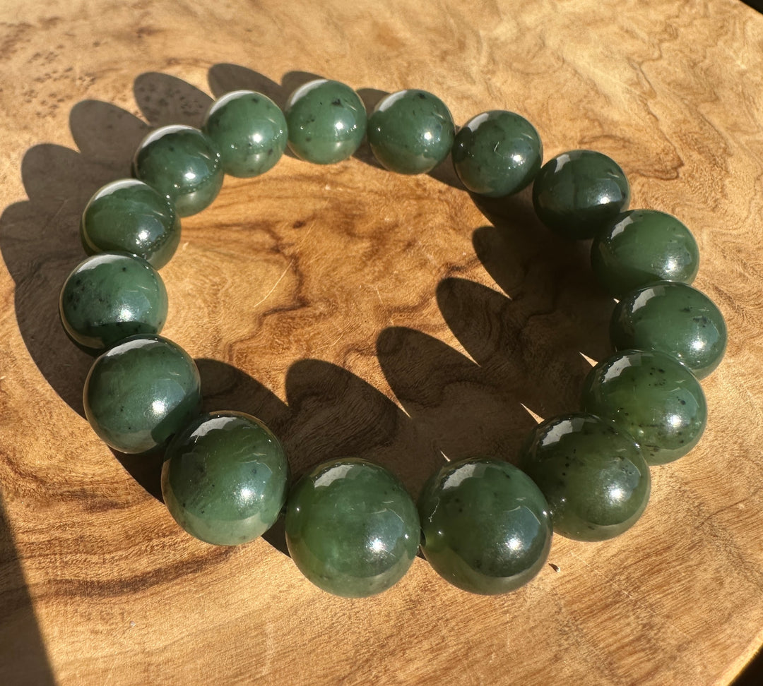 Close up of 12mm River Canadian nephrite jade beads forming a bracelet on a wooden surface
