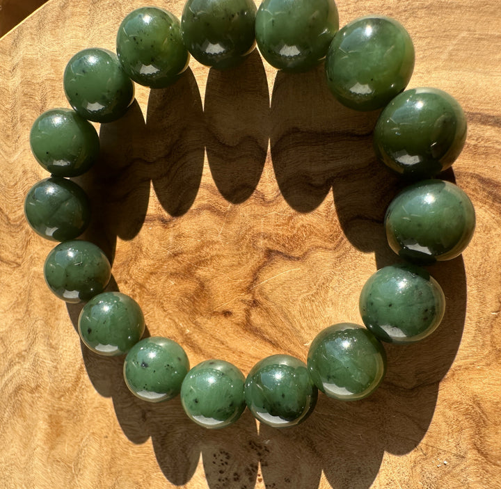 Green nephrite jade bead bracelet with polished 12mm beads on a wooden surface