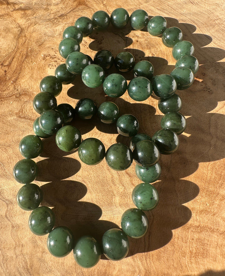 Row of 12mm River Canadian nephrite jade beads laid on wood