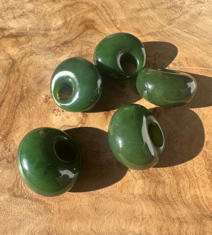 Green jade donut beads on a wooden surface