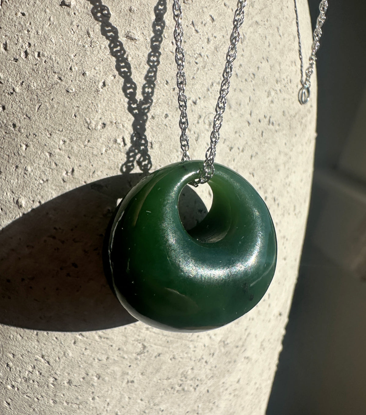 Green Cassiar jade donut pendant with hole in center on a silver chain