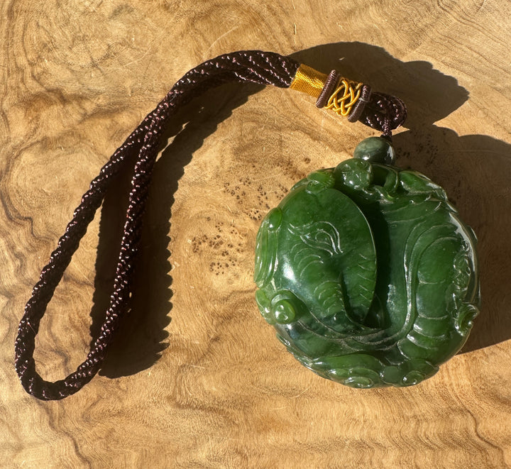 Nephrite jade pendant on a dark brown braided cord with a gold wrap