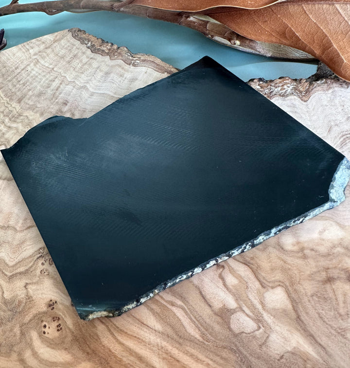 Wyoming Black Jade slab on a wooden surface with a rough natural edge