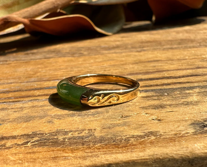 Ring R0392 two-tone ring with green enamel and gold-tone engraved side on a wooden surface.