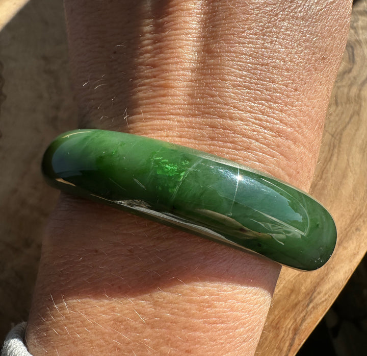 Close up of a green jade bangle on the wrist with sunlight reflections