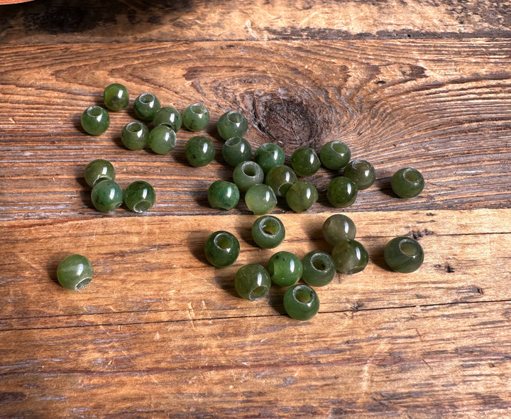 8mm Canadian jade beads with large holes arranged in a loose strand on a wooden table