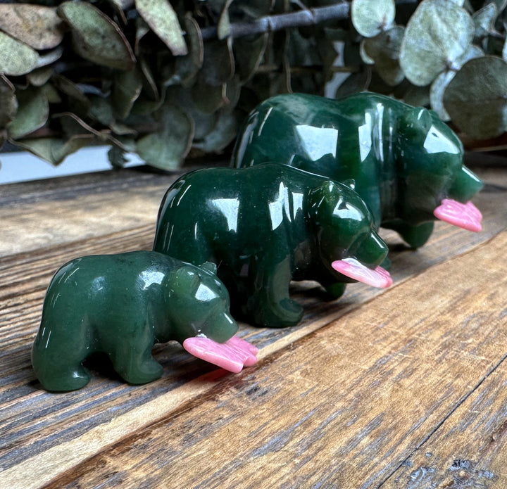 Three jade bears with pink rhodonite fish lined up on a wood surface with eucalyptus in the background