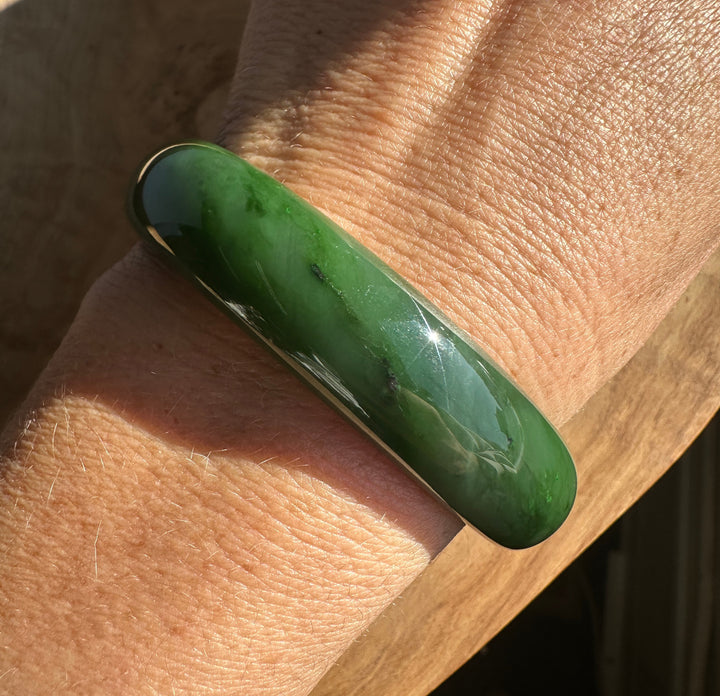 Close up of the jade bangle on the wrist showing green color and natural texture