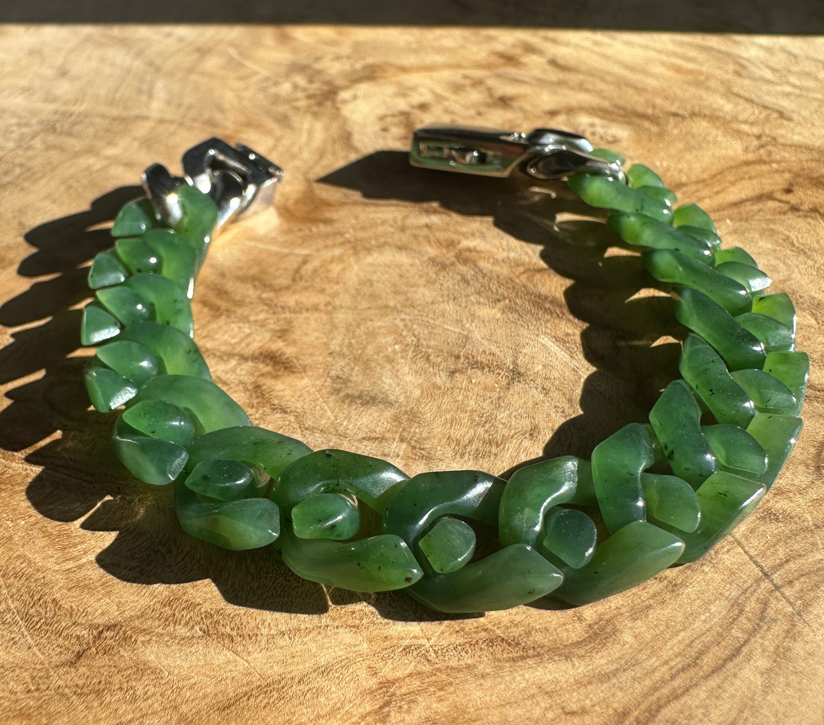 A Grade Canadian nephrite Cuban link bracelet in green, 7 inches, on wood with a silver clasp
