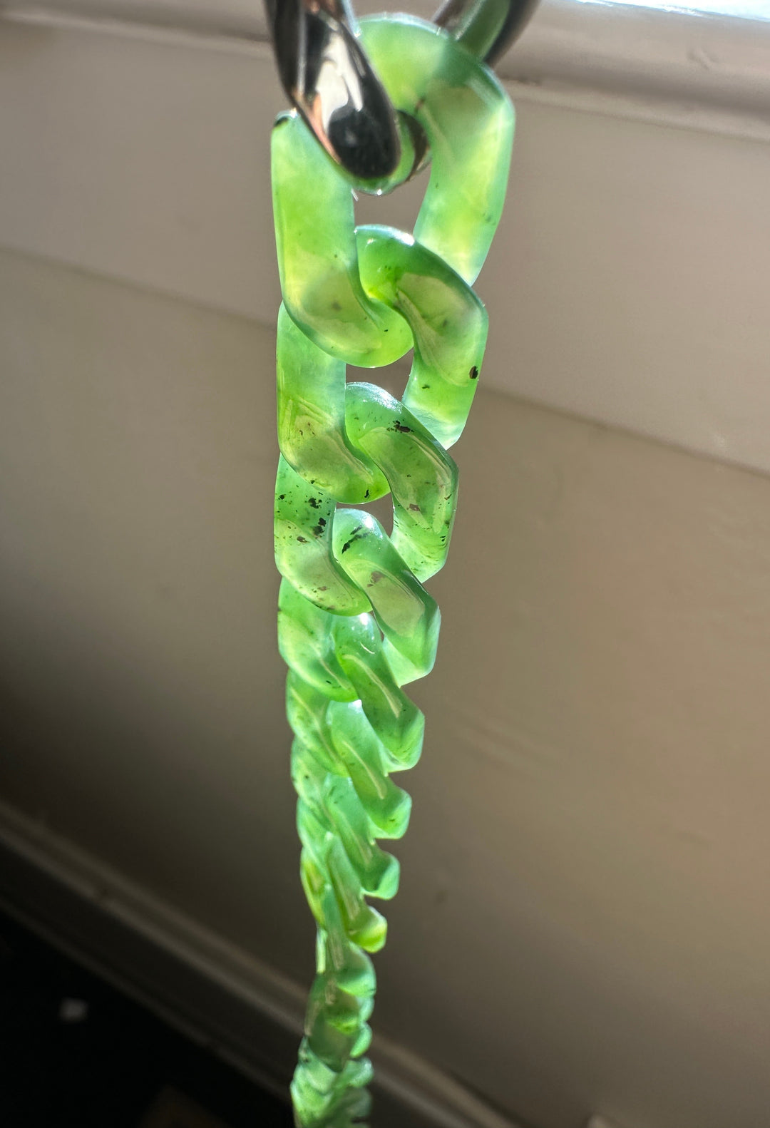 Close up of a vivid green nephrite Cuban link bracelet with chunky curved links and a metal clasp