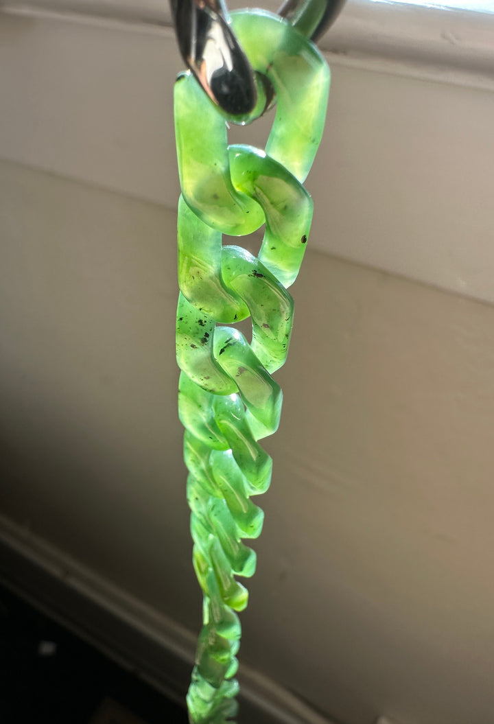 Close up of a vivid green nephrite Cuban link bracelet with chunky curved links and a metal clasp