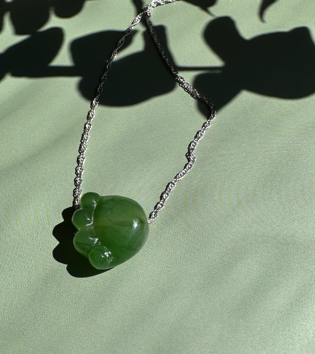Bright green jade cat paw pendant on a silver chain