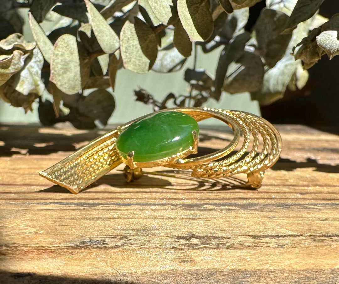 Green jade centerpiece set in ornate gold brooch with leaflike textured scales and curling bands