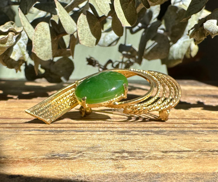 Green jade centerpiece set in ornate gold brooch with leaflike textured scales and curling bands