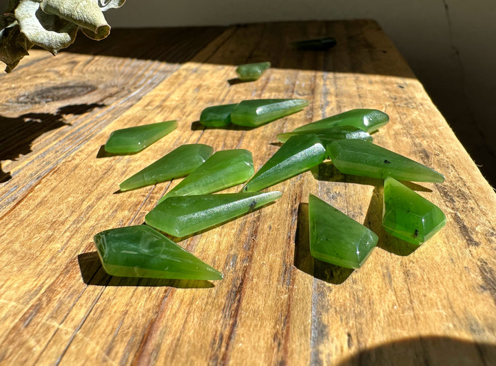 Vintage Nephrite jade kite beads in 10 and 20 mm sizes laid on a rustic wooden surface