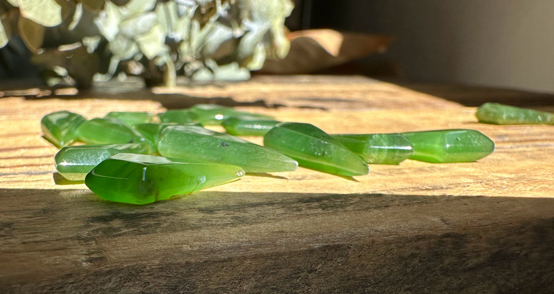 Loose Nephrite jade kite beads on a sunlit wooden surface
