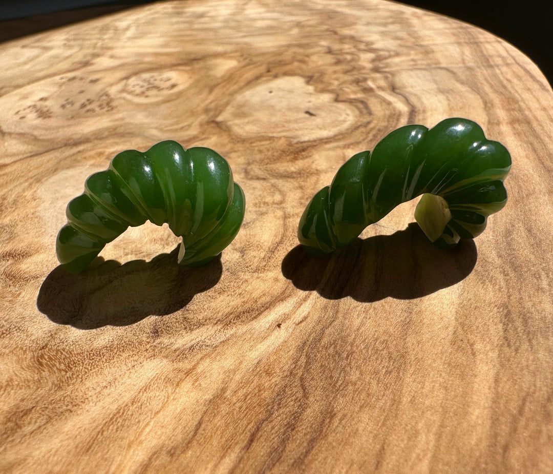 Top-down view of green jade fluted curved pair on wood showing scalloped edges