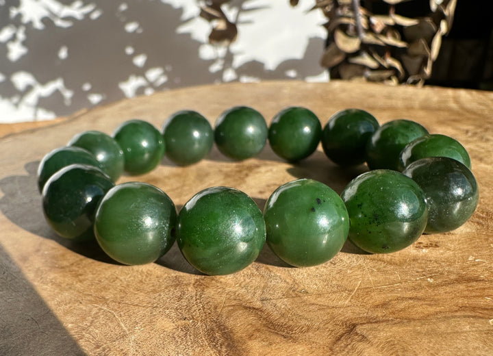 14mm Canadian nephrite jade bead bracelet laid on a wooden background