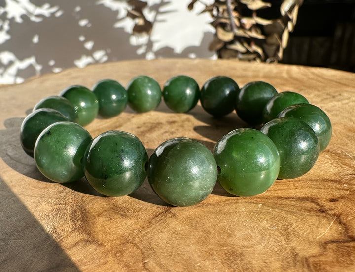 14mm Canadian nephrite jade bead bracelet resting on a warm wooden surface