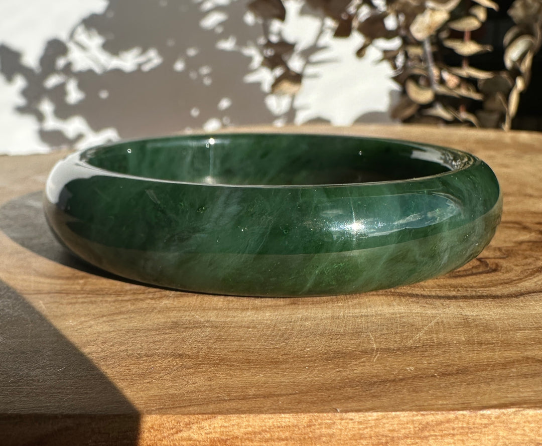 Green jade bangle with a smooth polished surface on a wooden table