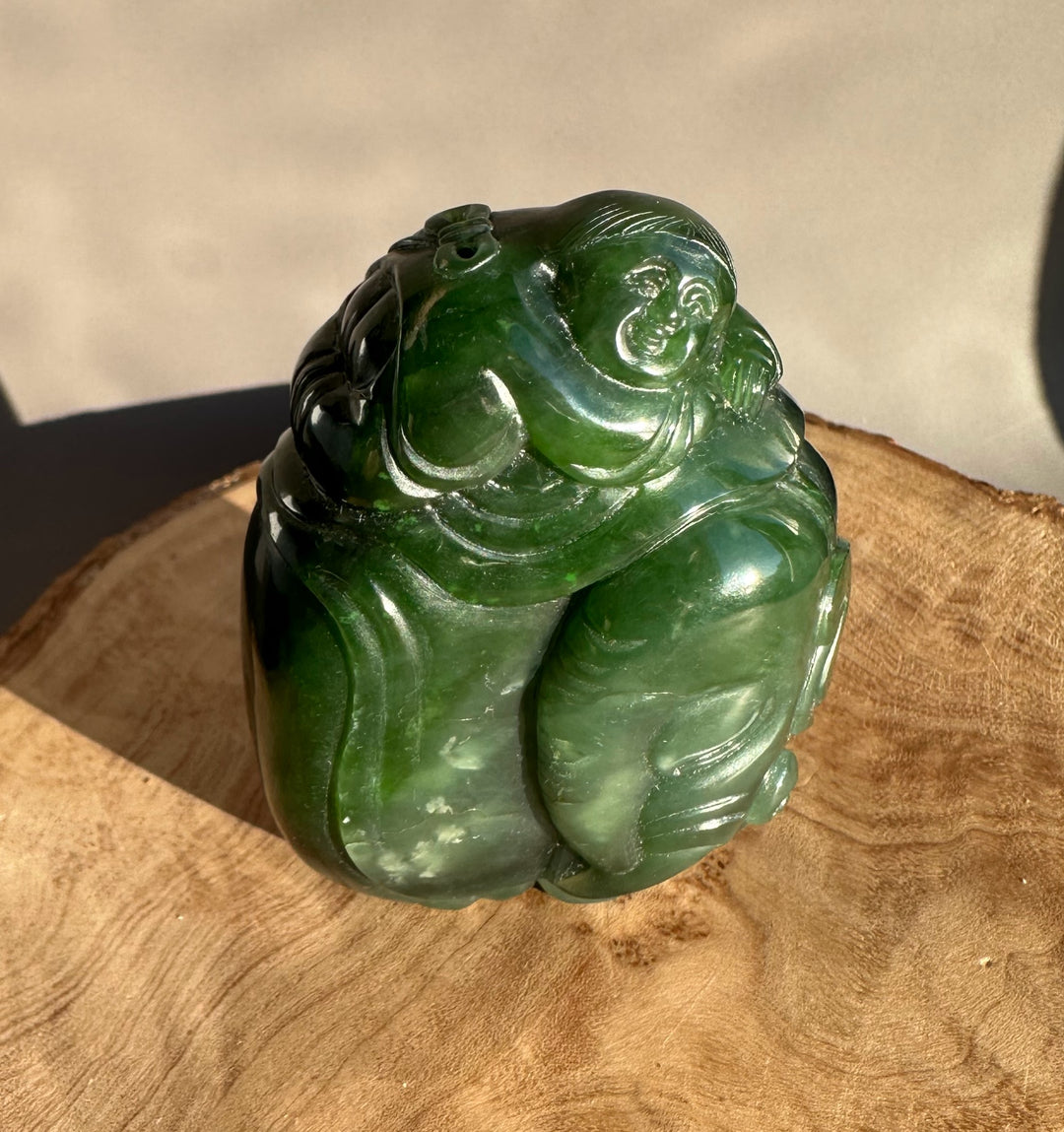 Front angle of the green jade figure capturing the smiling rider on the elephant and polished surface.