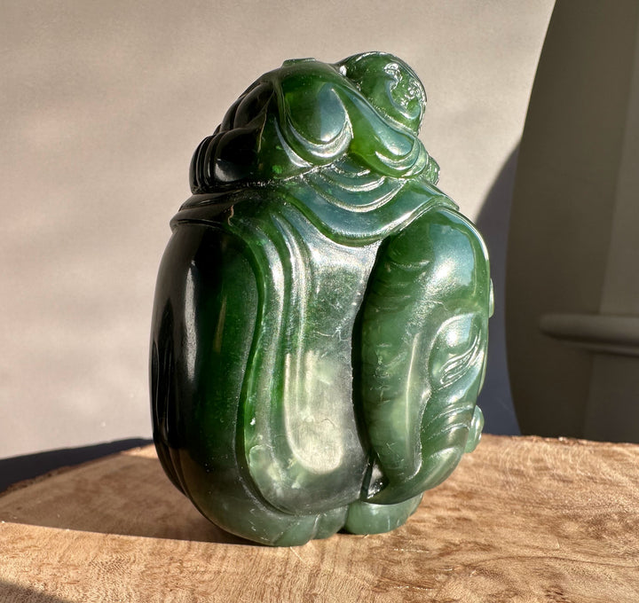 Dark green jade carving of a young boy riding an elephant with flowing robes.