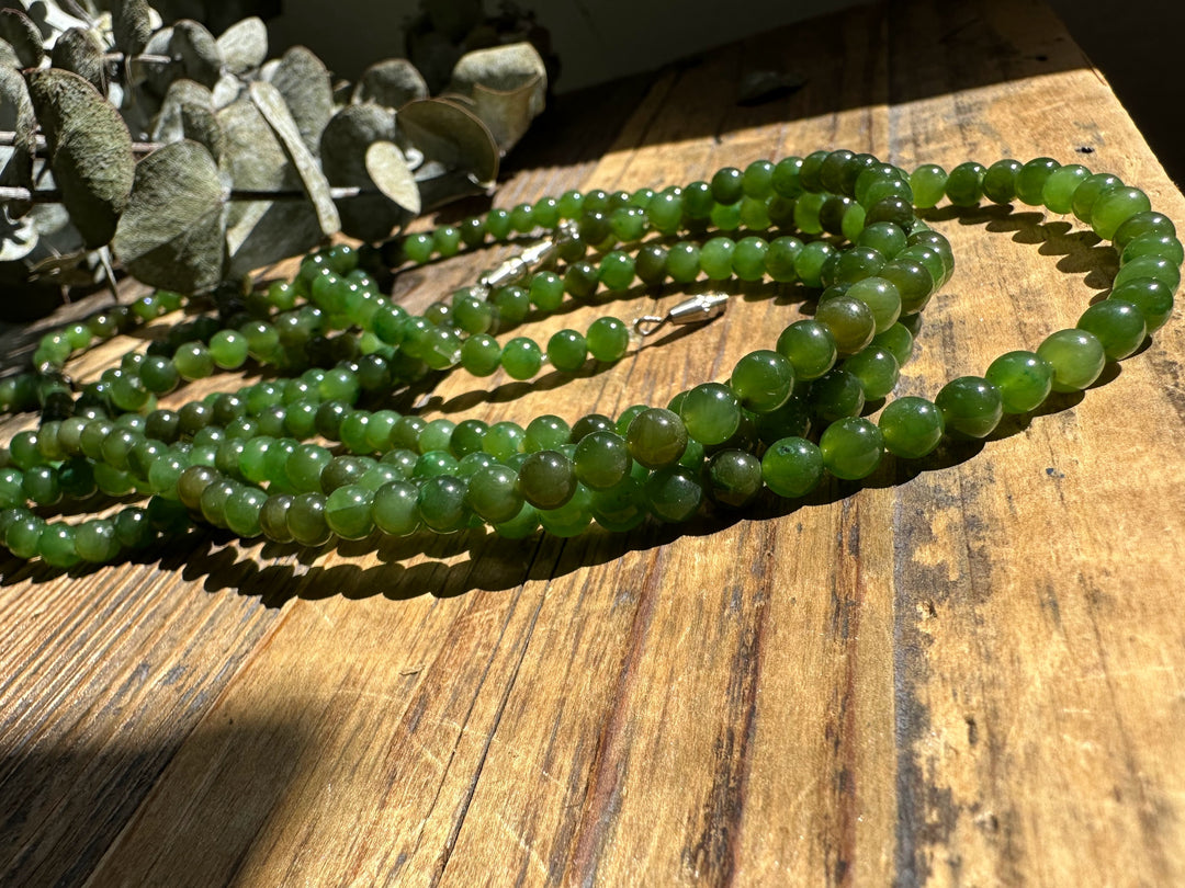 5mm Canadian nephrite jade bead strands on a sunlit wooden surface