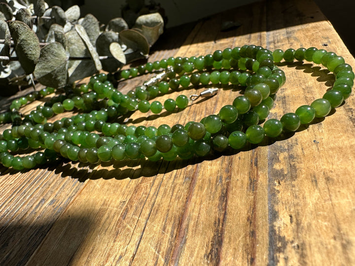 5mm Canadian nephrite jade bead strands on a sunlit wooden surface