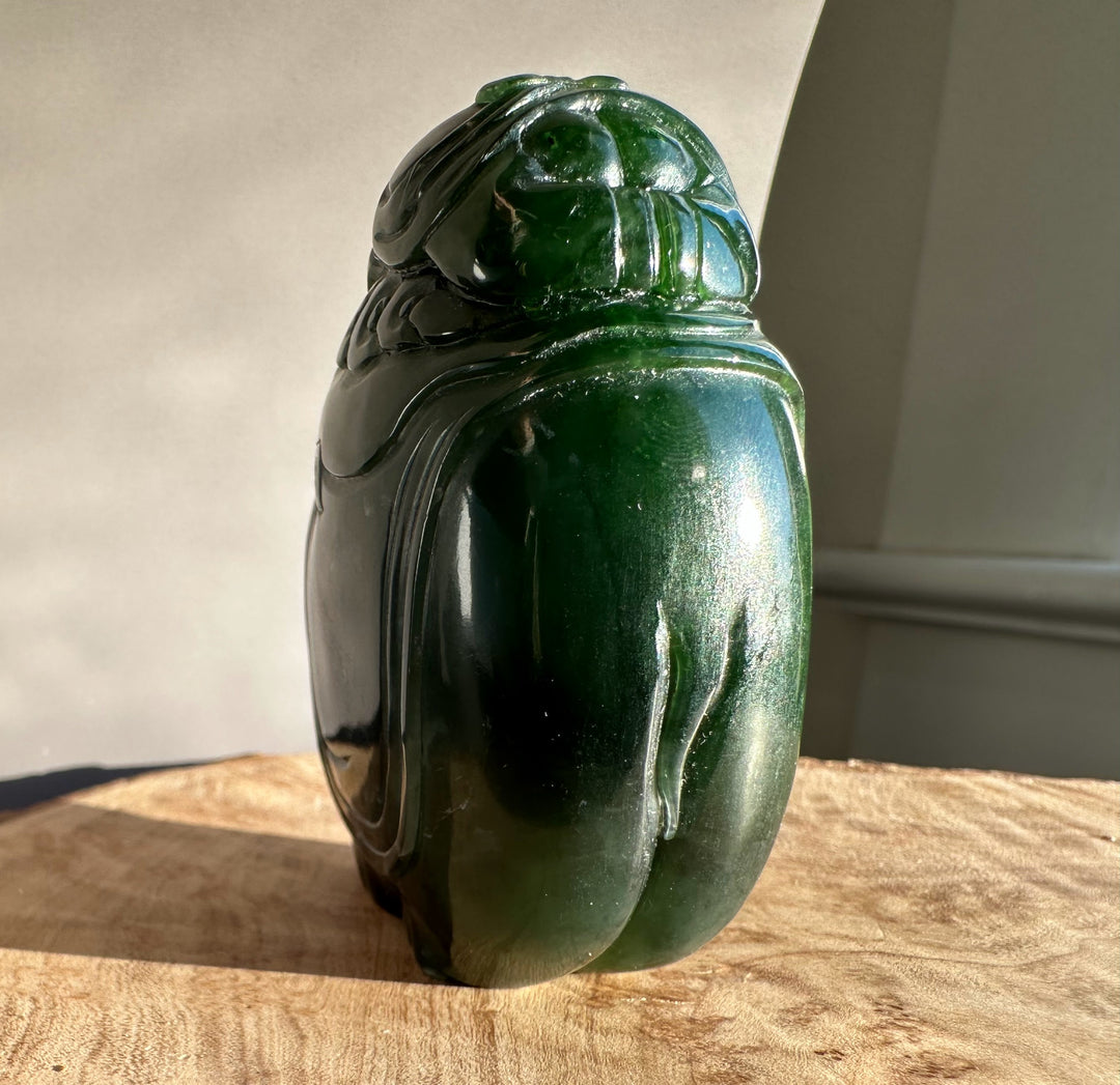Jade carving of a young boy riding an elephant in dark green stone