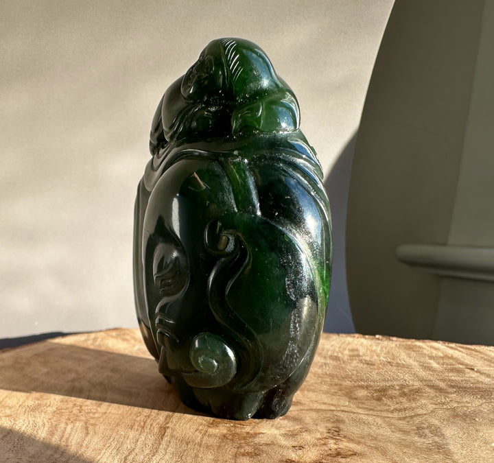 Rear view of a glossy dark green jade sculpture of a young boy riding an elephant