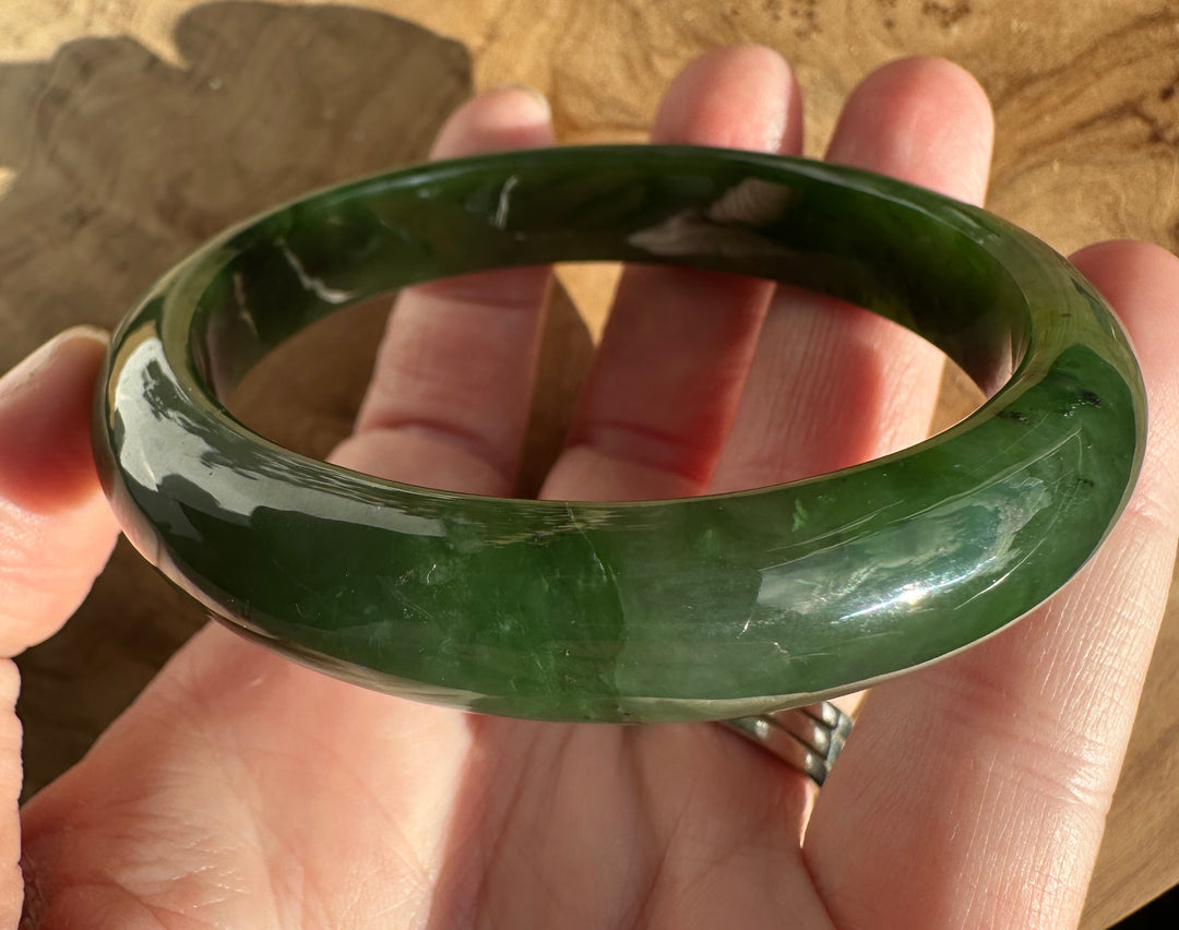 Jade Bangle 55.5 x 12mm held between fingers showing its curved inner edge